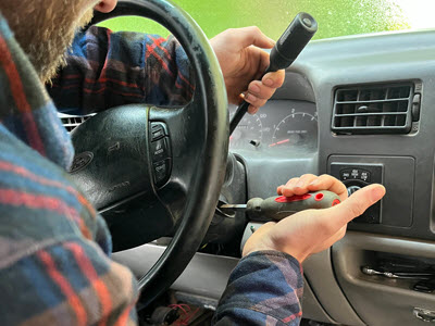 close up of someone using scredriver to start a truck