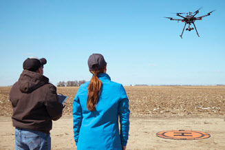 People flying drone over crops