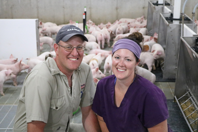 Dave & Lauren DeVries in swine barn smiling at camera