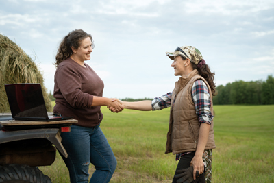 two farmers shaking hands in field