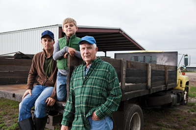 3 generations of farmers sitting on a truck
