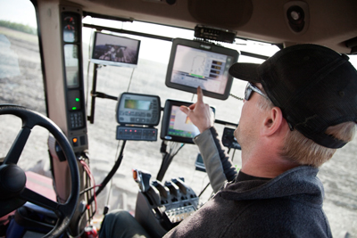 Farmer in tractor looking at guidance system screen