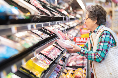 woman in grocery store looking at packaged meat