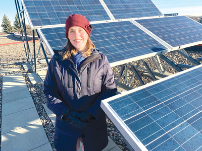 Heather Mackenzie standing next to solar panels