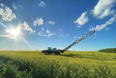Sprayer in a flowering field on a sunny day