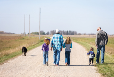 family walking down gravel road with dog 