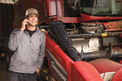 farmer leaning on truck talking on cell phone